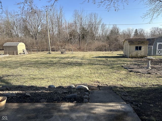 view of yard featuring a storage unit, an outdoor structure, and fence