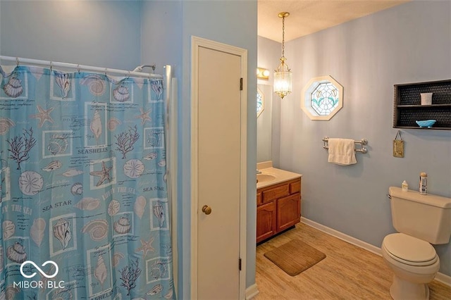 bathroom with toilet, curtained shower, wood finished floors, baseboards, and vanity