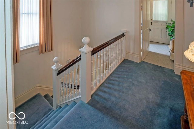 corridor featuring an upstairs landing, baseboards, and carpet