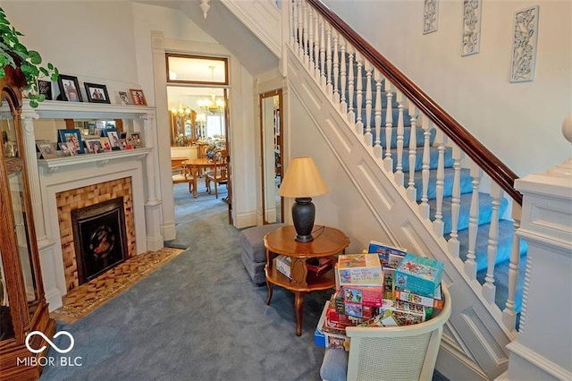 stairs featuring an inviting chandelier, carpet flooring, and a tile fireplace