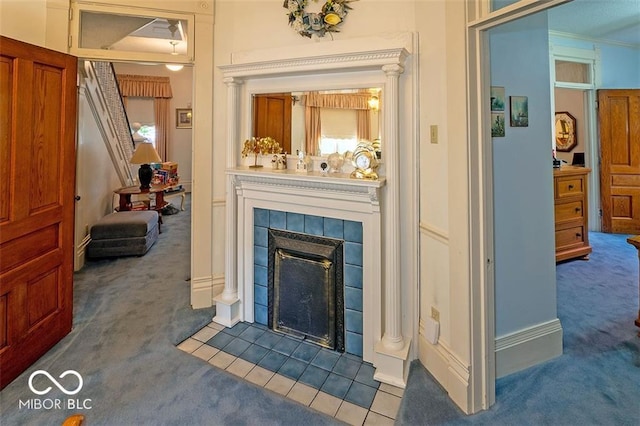 carpeted living room featuring a tiled fireplace and ornamental molding