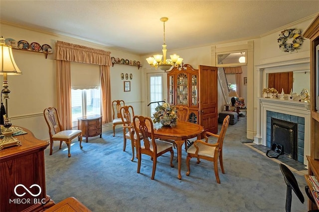 dining area with carpet, a chandelier, a tiled fireplace, and ornamental molding