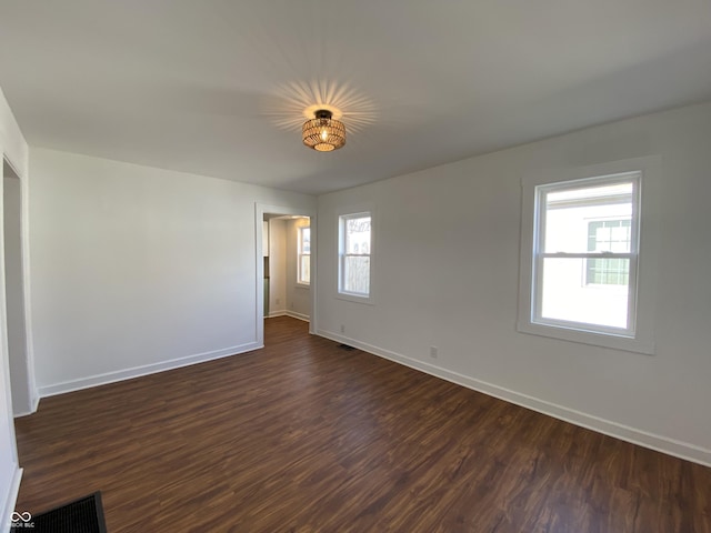 empty room with visible vents, baseboards, and dark wood finished floors