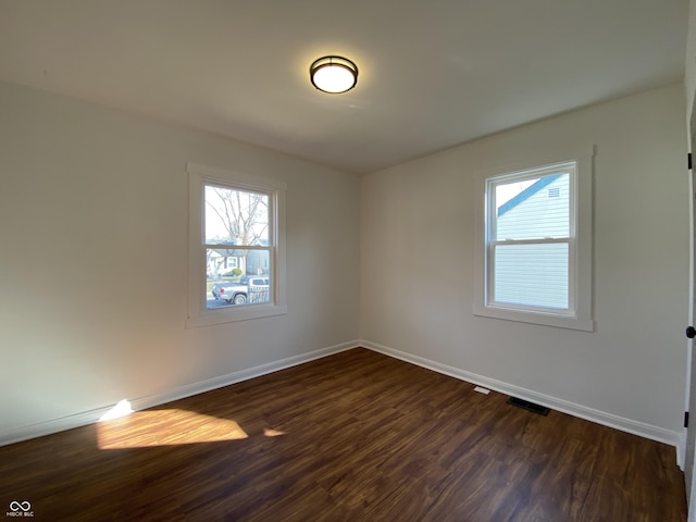 unfurnished room with a wealth of natural light, visible vents, and baseboards