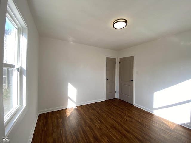 empty room with baseboards and dark wood-style flooring