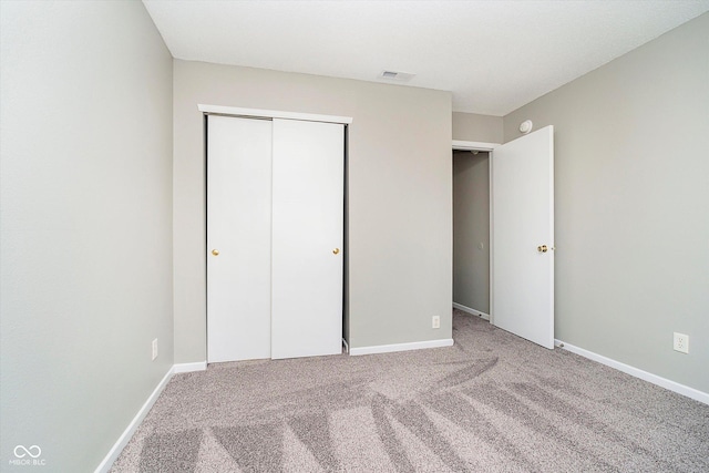 unfurnished bedroom with visible vents, carpet, a closet, and baseboards