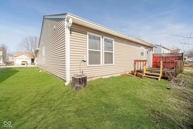 rear view of house featuring central AC unit, a wooden deck, and a yard