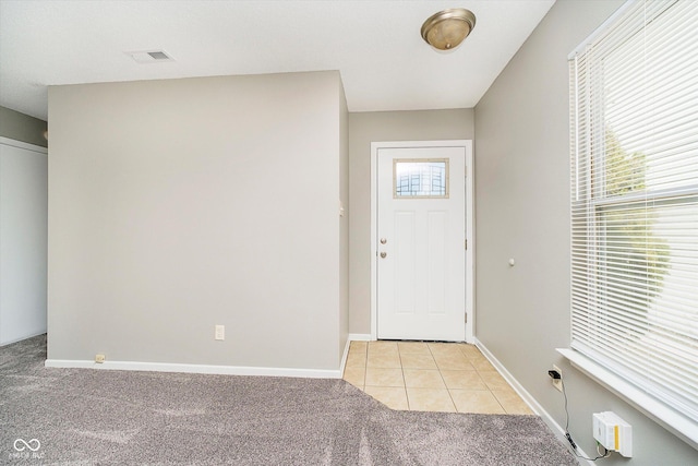 foyer entrance featuring light tile patterned floors, baseboards, visible vents, and light carpet