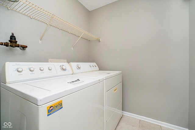 washroom with light tile patterned flooring, laundry area, baseboards, and separate washer and dryer