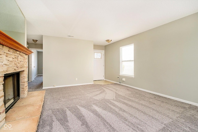 unfurnished living room featuring a stone fireplace, visible vents, baseboards, and carpet floors