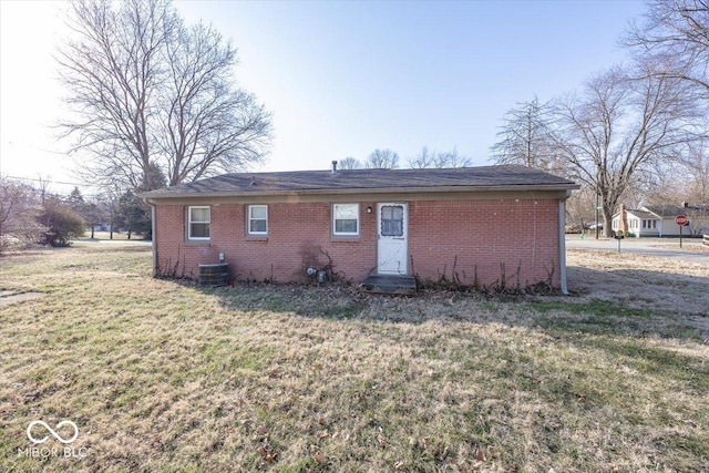 rear view of house featuring a yard, central air condition unit, and brick siding