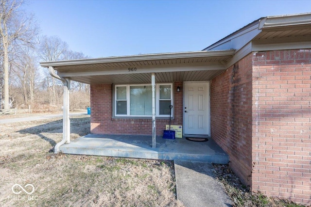 entrance to property with covered porch and brick siding