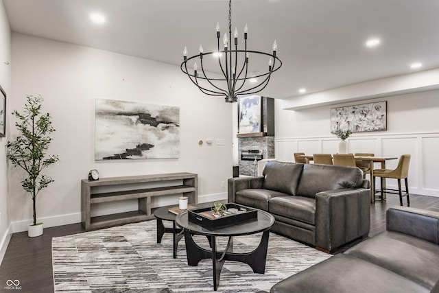 living room with baseboards, recessed lighting, an inviting chandelier, wood finished floors, and a decorative wall