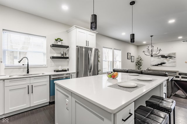 kitchen with dark wood finished floors, a kitchen bar, appliances with stainless steel finishes, white cabinets, and a sink