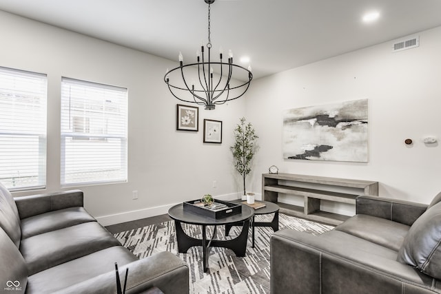 living area with an inviting chandelier, wood finished floors, baseboards, and visible vents