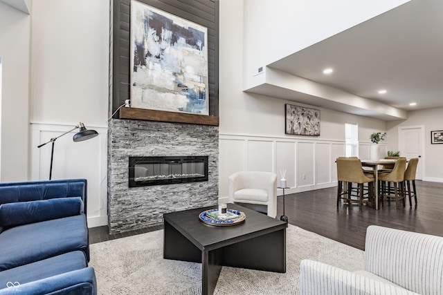 living room featuring recessed lighting, wood finished floors, a fireplace, and a decorative wall