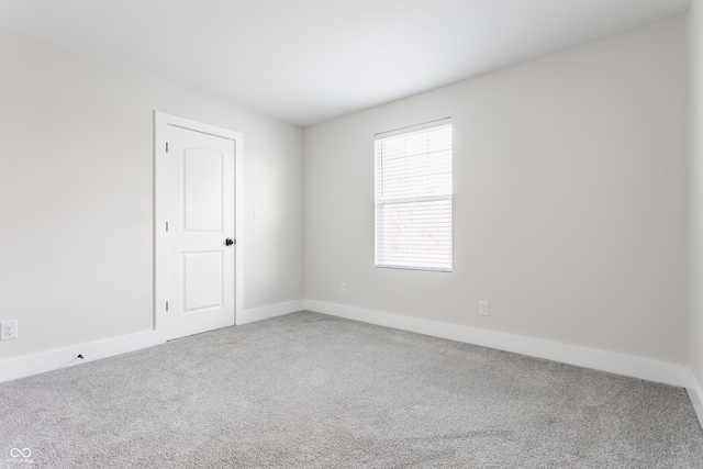 carpeted empty room featuring baseboards