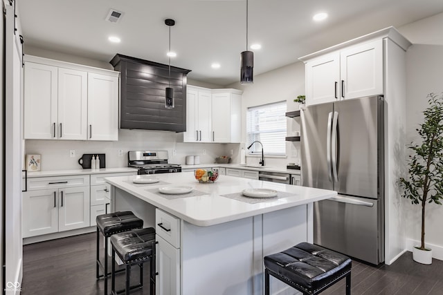 kitchen featuring a breakfast bar, dark wood-style flooring, appliances with stainless steel finishes, white cabinetry, and a center island