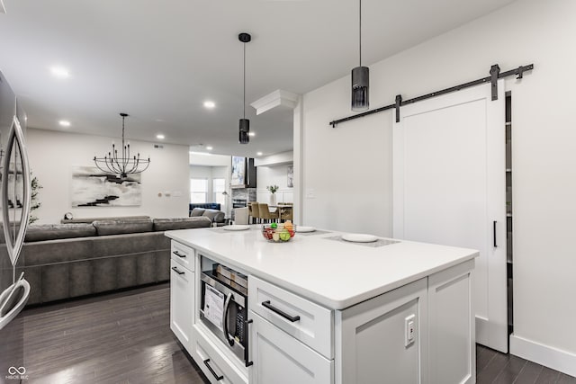 kitchen with stainless steel appliances, dark wood-type flooring, white cabinets, a barn door, and open floor plan