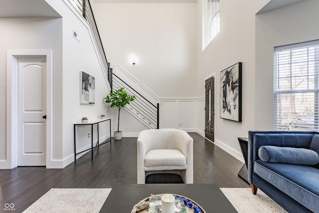 living area with visible vents, wood finished floors, stairway, a high ceiling, and baseboards