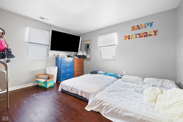 bedroom featuring visible vents, baseboards, and wood finished floors