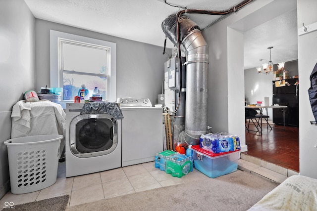 laundry area featuring washer and clothes dryer, laundry area, tile patterned flooring, and a chandelier