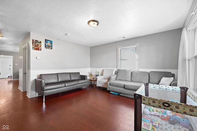 living room with visible vents, a textured ceiling, and wood finished floors