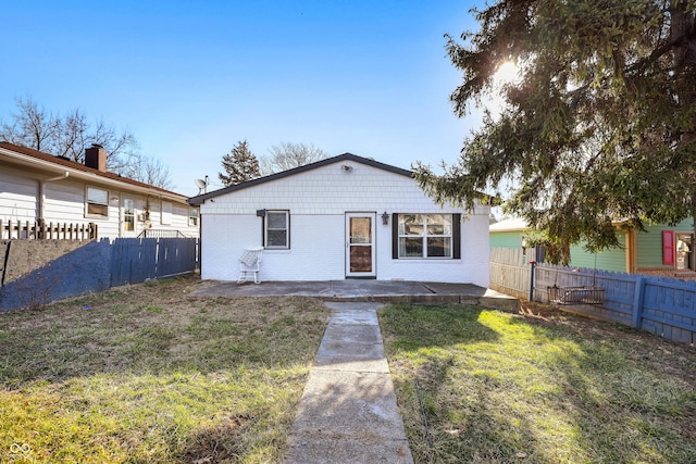 bungalow-style home with brick siding, a patio area, a front yard, and a fenced backyard