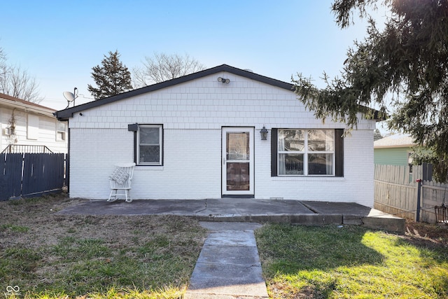 view of front of home with brick siding, a front lawn, a patio, and fence