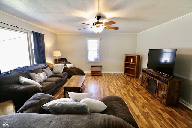 living room featuring crown molding, wood finished floors, baseboards, and ceiling fan