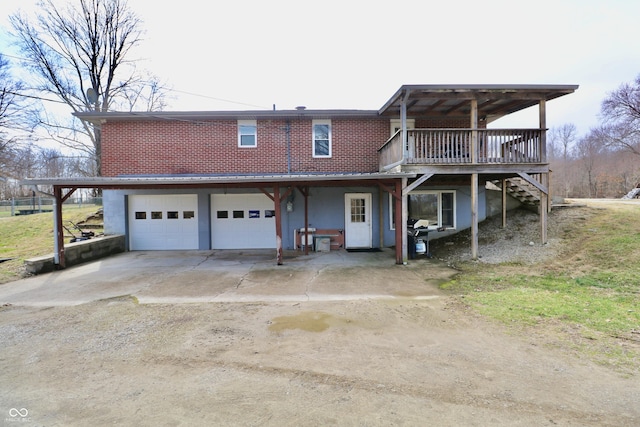 rear view of property with driveway, a deck, and an attached garage