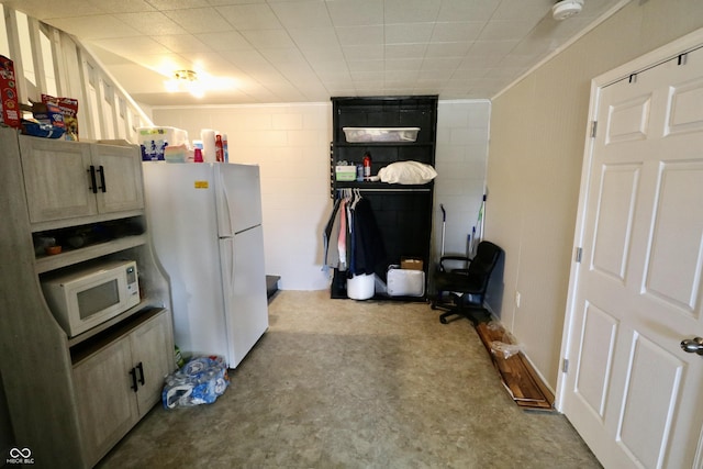 kitchen with white appliances and concrete block wall