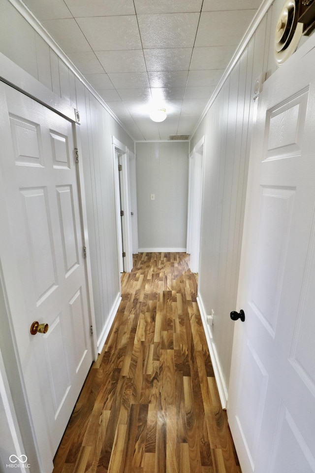 hallway with baseboards, wood finished floors, and crown molding