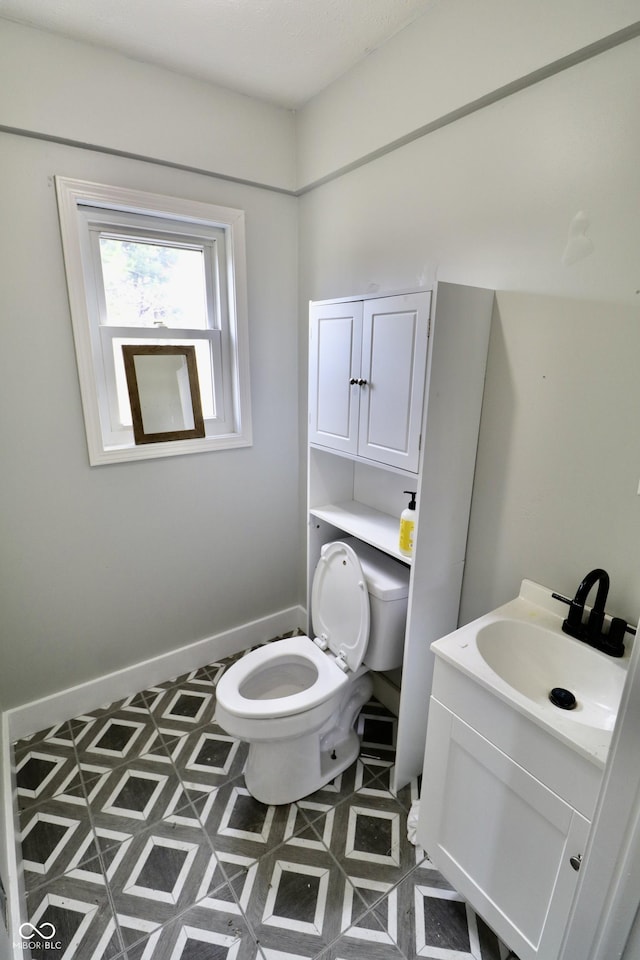 bathroom with toilet, vanity, and baseboards