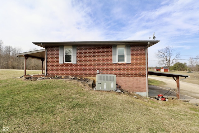 exterior space with central air condition unit, a lawn, and brick siding