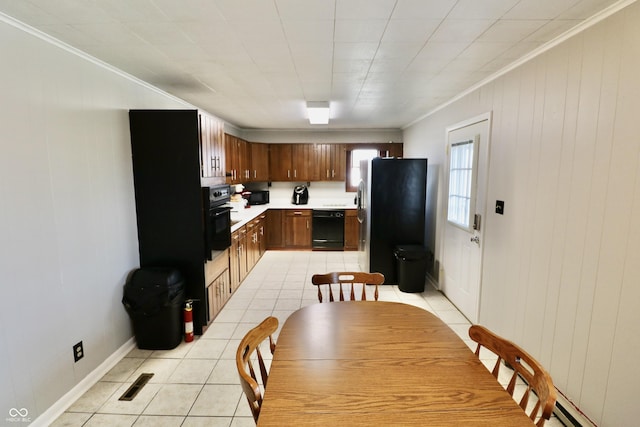 kitchen with crown molding, baseboards, light countertops, light tile patterned flooring, and black appliances