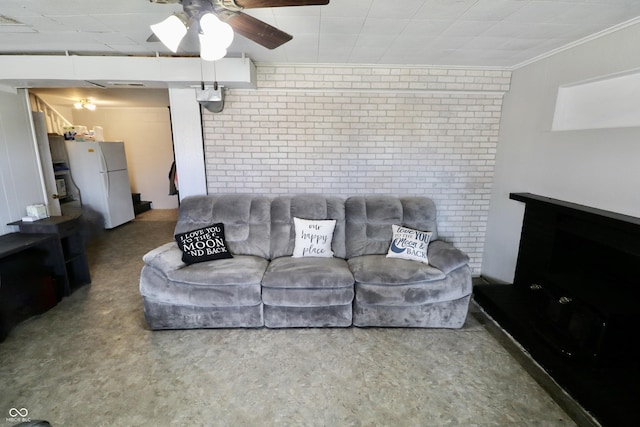 living room with brick wall, crown molding, and ceiling fan