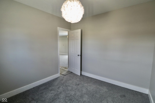 empty room featuring baseboards, carpet, and a chandelier