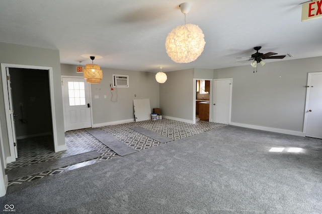 interior space featuring ceiling fan with notable chandelier, baseboards, carpet floors, and a wall mounted AC