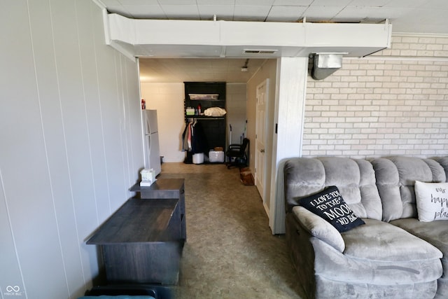 living area featuring visible vents and brick wall