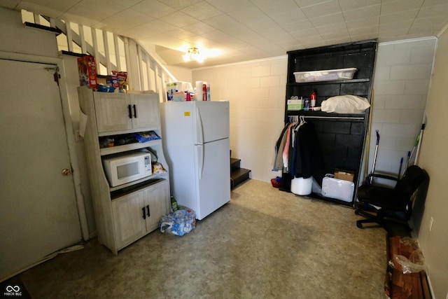 kitchen with white appliances and concrete block wall