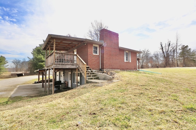 back of house featuring stairway, a yard, a chimney, a deck, and brick siding