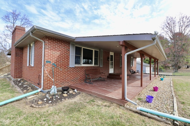 view of property exterior with a carport, brick siding, a chimney, and fence