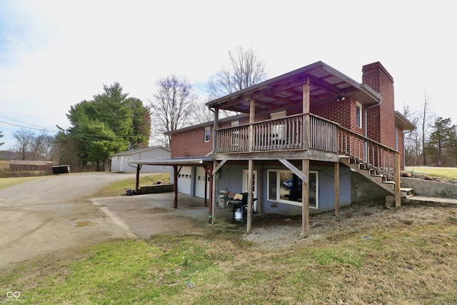 back of house featuring brick siding, a wooden deck, stairs, a chimney, and an attached garage