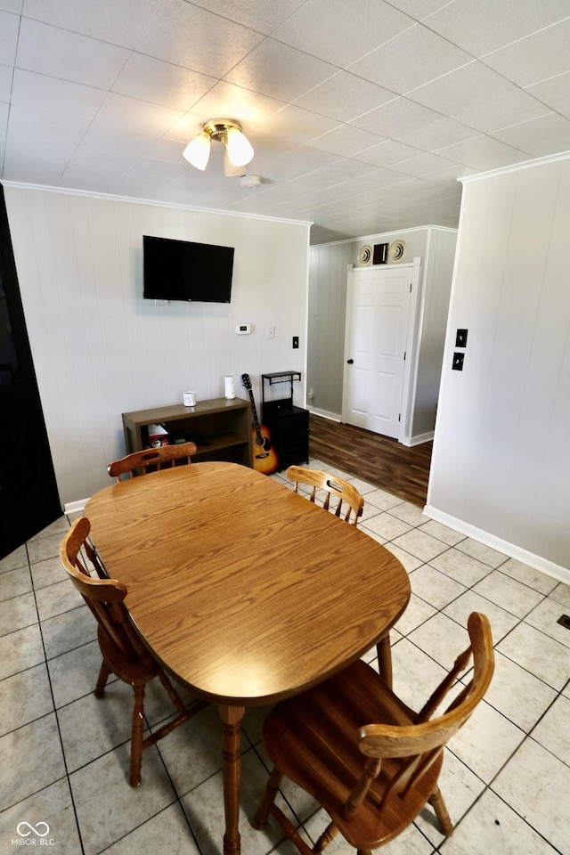 dining space with light tile patterned flooring, crown molding, and baseboards