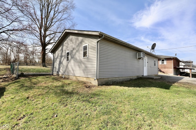 view of side of property featuring a wall unit AC, a lawn, and fence