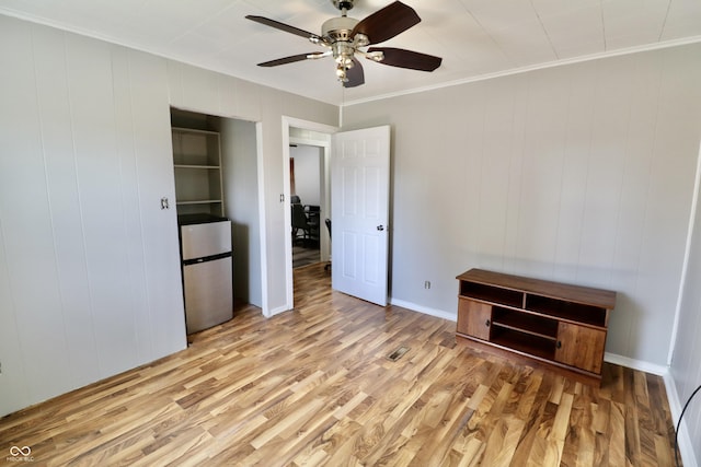 unfurnished bedroom featuring ceiling fan, wood finished floors, crown molding, and freestanding refrigerator