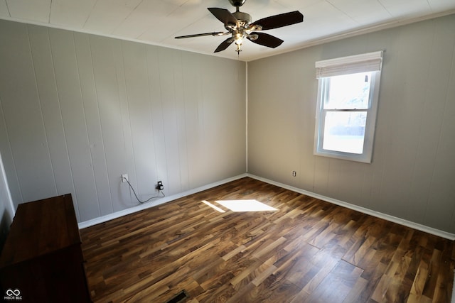 unfurnished room with baseboards, ceiling fan, dark wood-style flooring, and ornamental molding