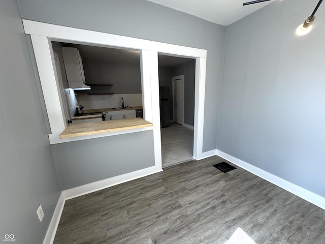 interior space featuring visible vents, a sink, baseboards, and wood finished floors