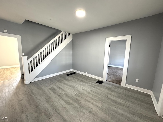 empty room with stairway, baseboards, and wood finished floors